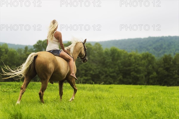 Woman horseback riding in countryside