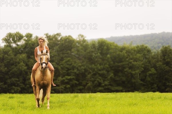 Woman horseback riding in countryside