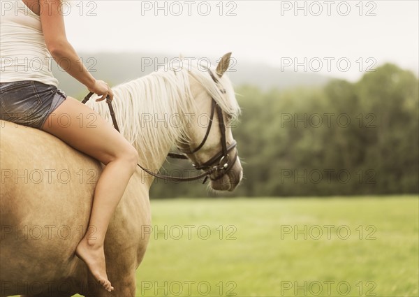 Woman horseback riding in countryside