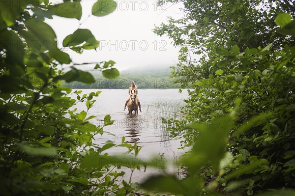 Woman horseback riding in countryside