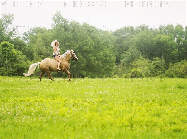 Woman horseback riding in countryside