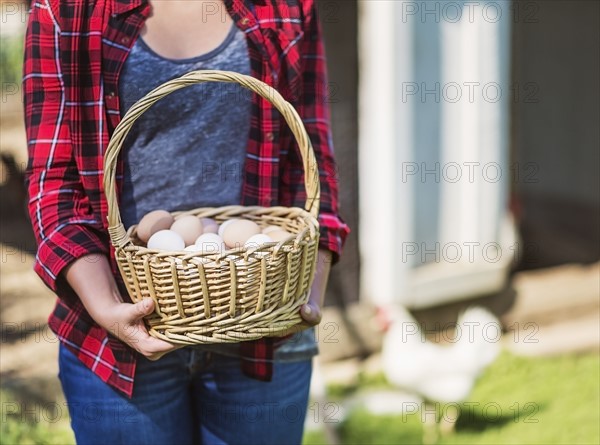 Female farmer carrying basket with eggs