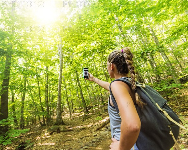 Female hiker looking at compass on phone