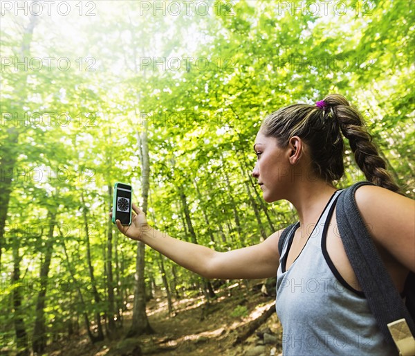 Female hiker looking at compass on phone