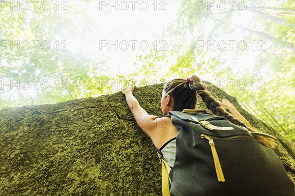 Young woman climbing on rock in forest