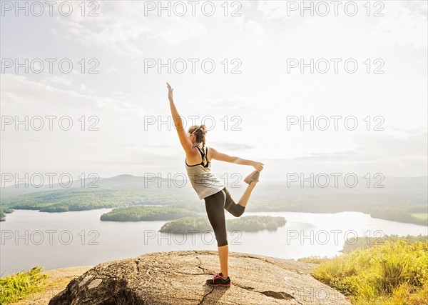 Side view of young woman exercising on mountain top
