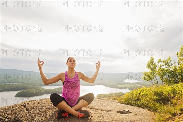 Young woman in lotus position against lake