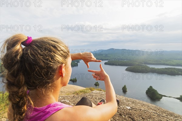 Young woman framing view of lake with hands