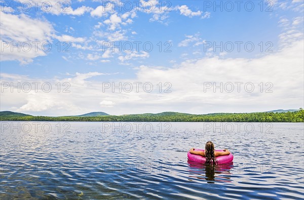 Young woman relaxing on lake in pool raft