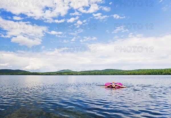 Young woman relaxing on lake in pool raft