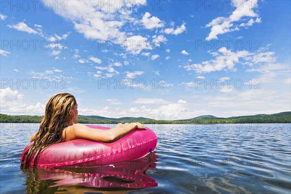 Young woman relaxing on lake in pool raft