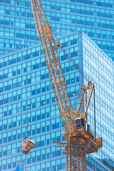 Low angle view of crane against skyscraper