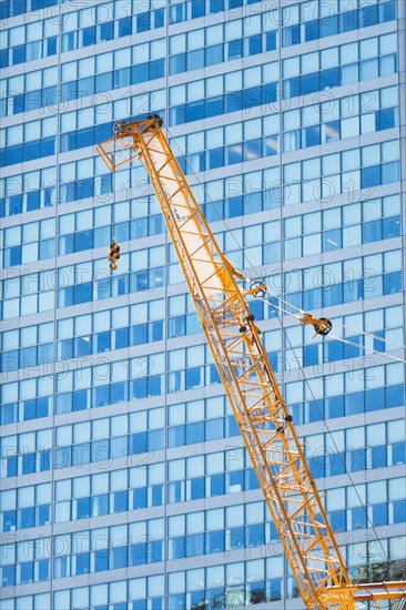 Low angle view of crane against skyscraper