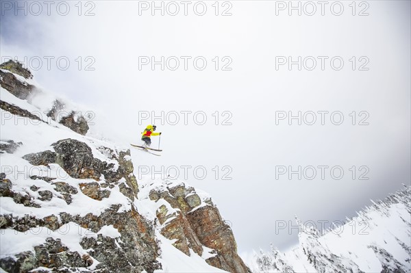 Skier jumping off rocky mountain