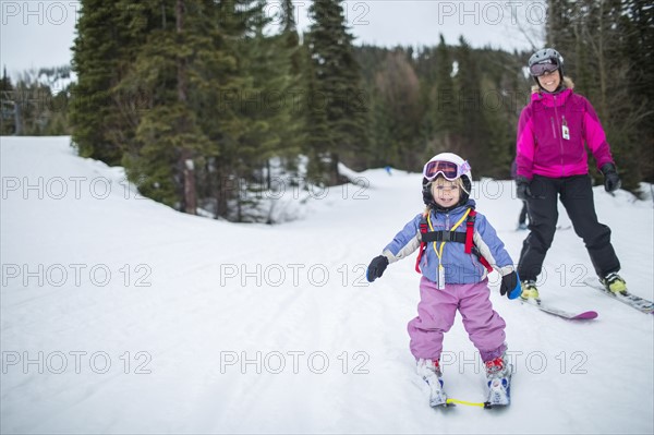 Little girl (2-3) learning skiing with mother