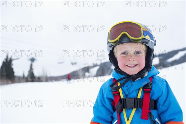 Smiley little boy (5) wearing ski suit in mountains