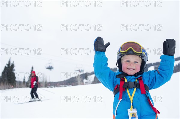 Smiley little boy (5) wearing ski suit in mountains