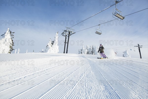 Mid-adult woman on ski slope under cable car