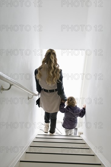 Mother and son (4-5) walking down stairs