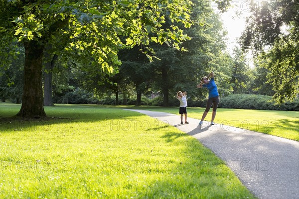 Mother and son (12-13) exercising in park