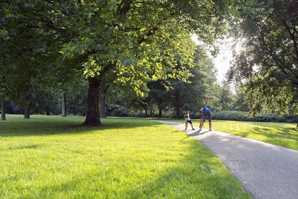 Mother and son (12-13) exercising in park