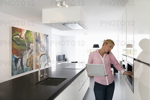 Woman with laptop in kitchen