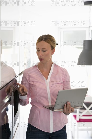 Woman with laptop in kitchen