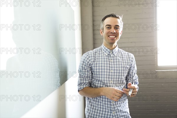 Smiling man standing next to whiteboard