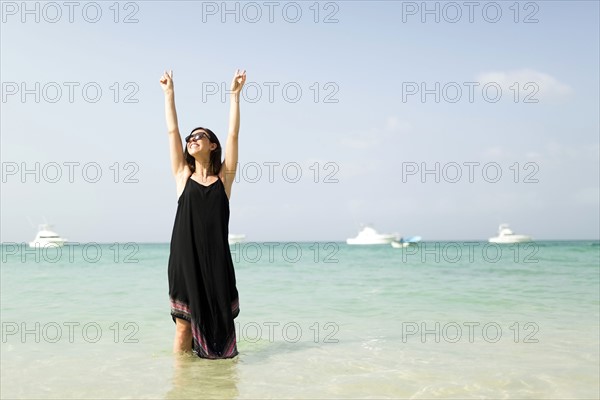 Woman with arms raised on beach