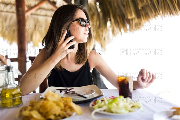 Woman by table, using phone