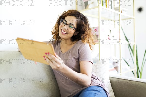 Woman sitting on sofa, using digital tablet