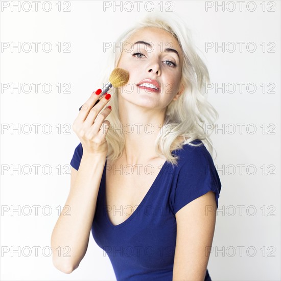 Studio shot of woman using make-up brush
