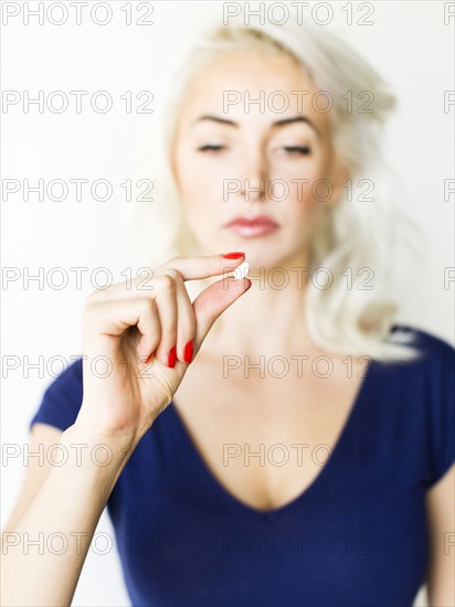 Studio shot of woman holding pill