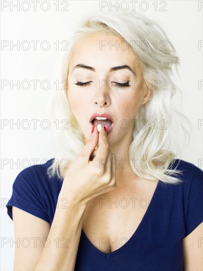 Studio shot of woman taking pill