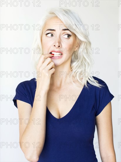 Studio shot of woman biting nails