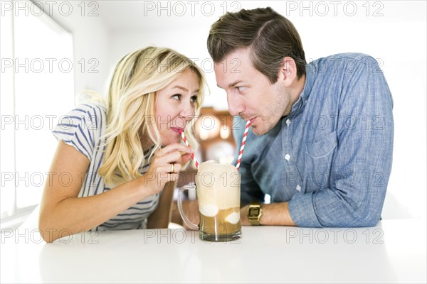 Couple drinking beer from drinking straw