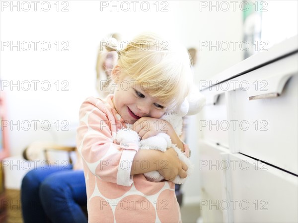 Girl (2-3) embracing toy