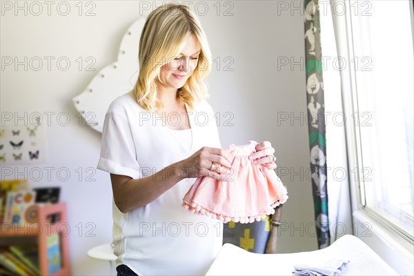 Pregnant woman holding baby clothing