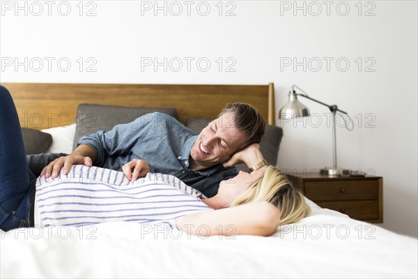 Husband lying down on bed with pregnant wife