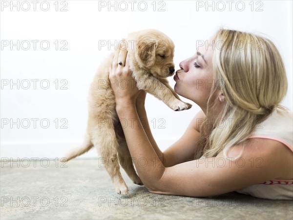 Owner kissing Golden Retriever puppy