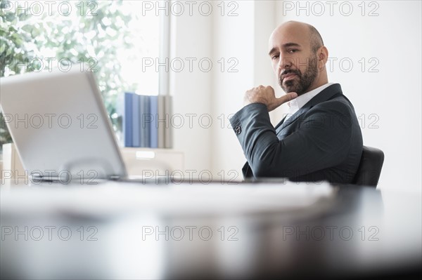 Serious businessman sitting at desk in office.