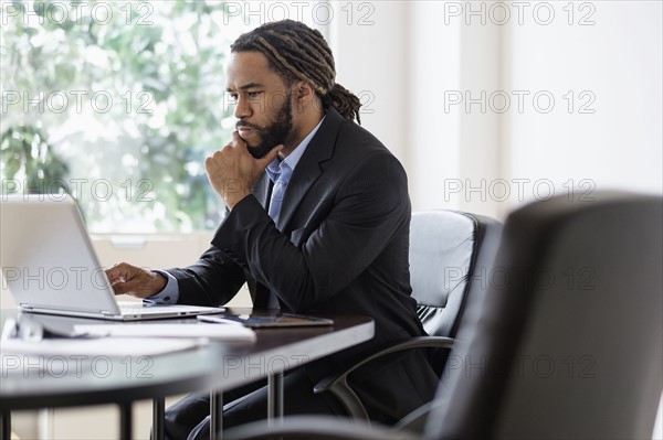 Concentrated businessman working with laptop at desk in office.