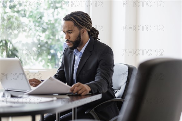Concentrated businessman working with laptop at desk in office.