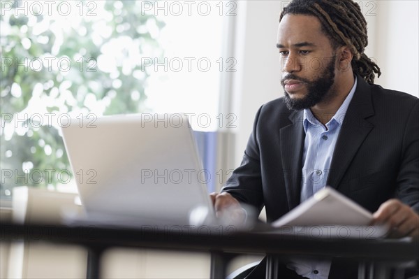 Concentrated businessman working with laptop at desk in office.