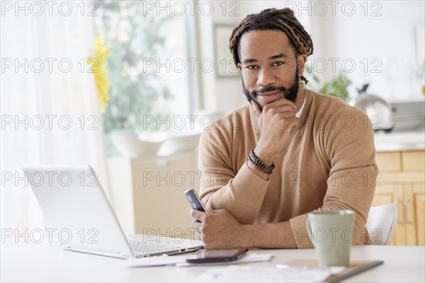 Portrait of young man with laptop at table.