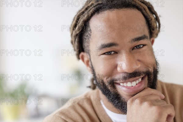 Portrait of smiley young man with hand on chin.