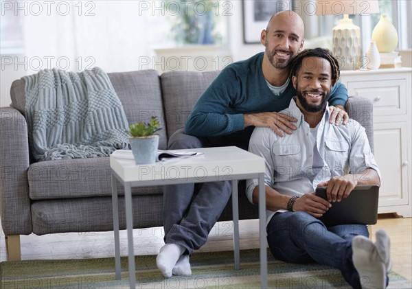 Man massaging boyfriend by sofa in living room.