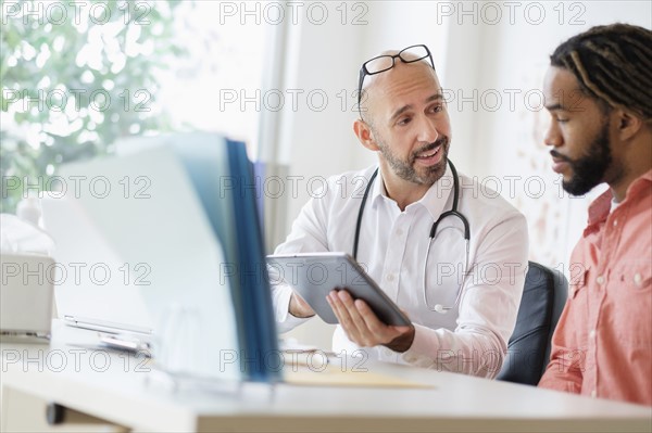 Doctor giving consultation to patient using digital tablet.