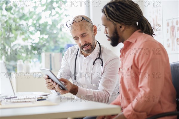 Doctor giving consultation to patient using digital tablet.