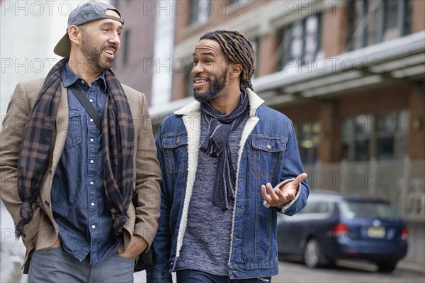 Smiley homosexual couple walking down street.